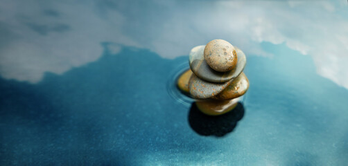 Harmony, Calm, Mind, Life Relaxing and Living by Nature Concept. Natural Stone Stack Setting on Water. Balancing Body, Mind, Soul and Spirit. Mental Health Practice. Cloudy Sky as Reflection