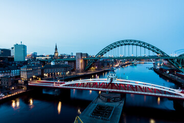 Fototapeta premium Newcastle upon Tyne UK: 30th March 2021: Newcastle Gateshead Quayside at night, with of Tyne Bridge and city skyline, long exposure during blue hour