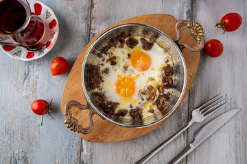 Turkish scrambled eggs with roasted meat in copper pan