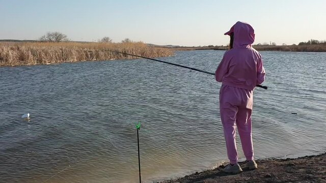 a teenage girl is fishing on the river bank on a spring day