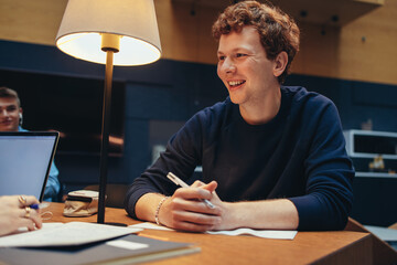 Cheerful male student studying in college library