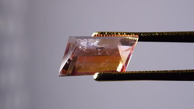 natural ametrine in the tweezers on the background
