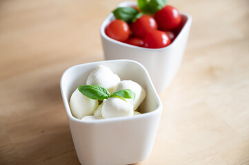 tomato mozarella in small bowls on a wooden table for brunch