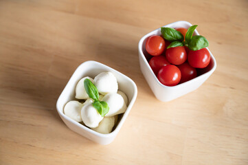 tomato mozarella in small bowls on a wooden table for brunch