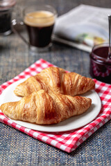Breakfast with croissants, marmalade and coffee with a newspaper on the background.