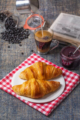 Breakfast with croissants, marmalade and coffee with a newspaper on the background.