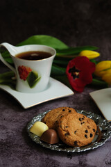 one white cup of tea and yellow and red tulips