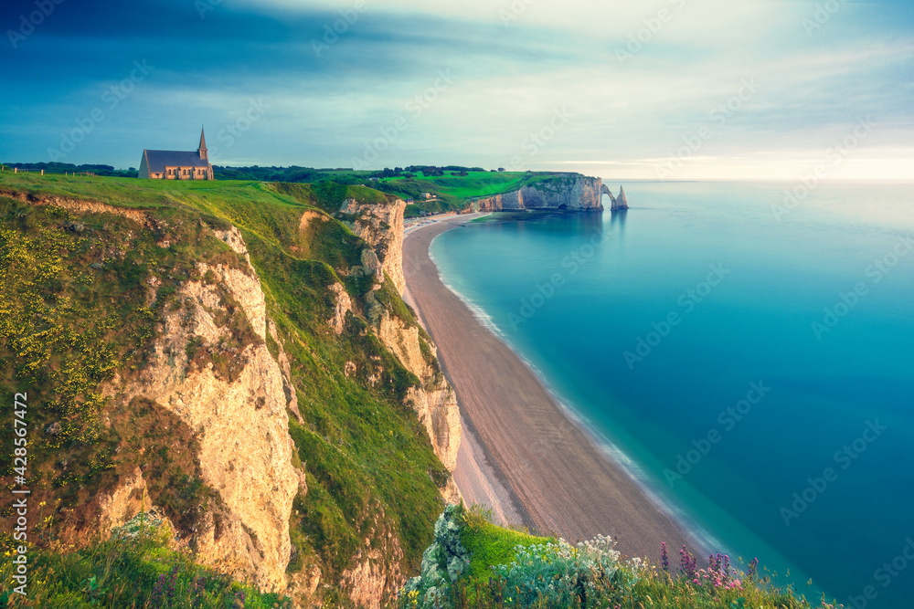 Wall mural The chalk cliffs, the church and the beach of Etretat during the golden hour. Etretat, Normandy, France