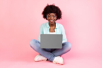 Happy African American Woman Using Laptop Sitting Over Pink Background