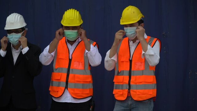 group of asian container cargo warehouse worker wearing and checking protective face mask standing over container box in Logistics transportation industry