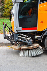 The rotating front sweeper car brushes remove fallen leaves from the road.