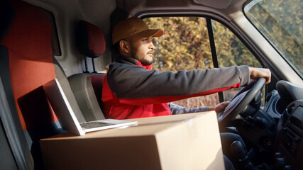 Courier driving the van with cardboard box on the seat. High quality photo