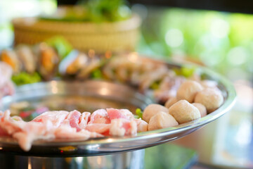closeup jaew hon or isan hot pot with raw pork meat ball and seafood with boiling spicy thick soup in silver ware pot for lunch or dinner and thai street food at restaurant