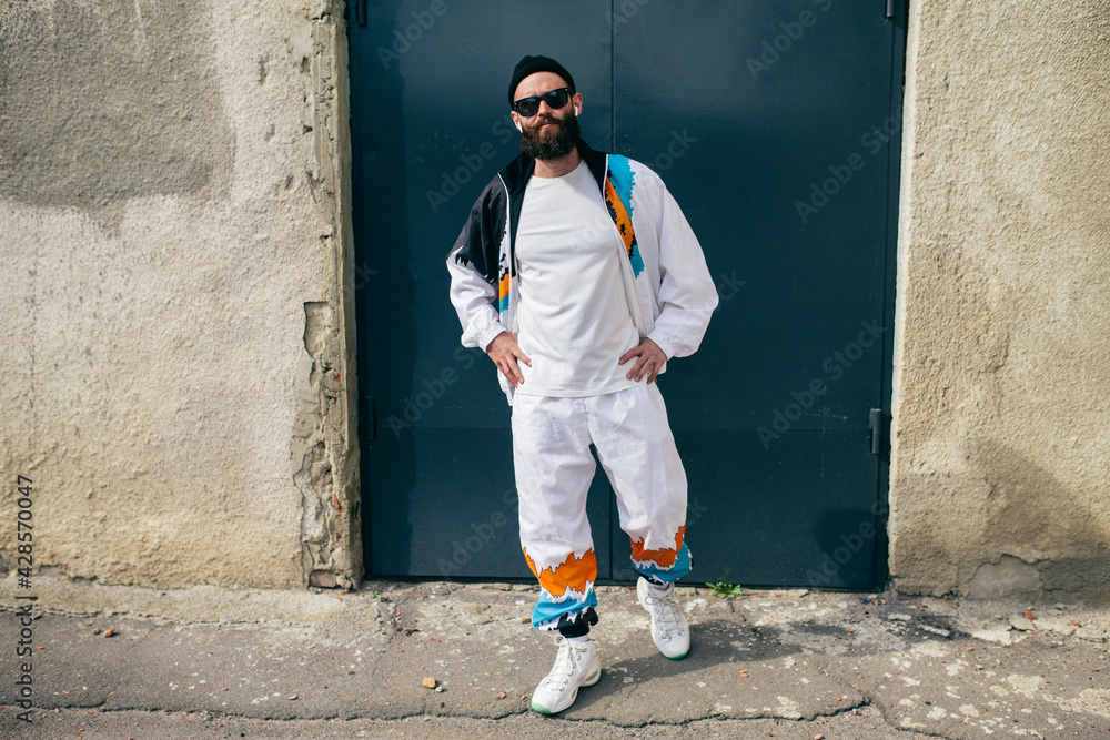 Sticker young bearded hipster guy wearing a vintage tracksuit and white blank t-shirt. mock-up for print. t-