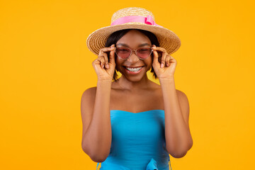 Portrait of beautiful African American woman in trendy summer outfit on orange studio background