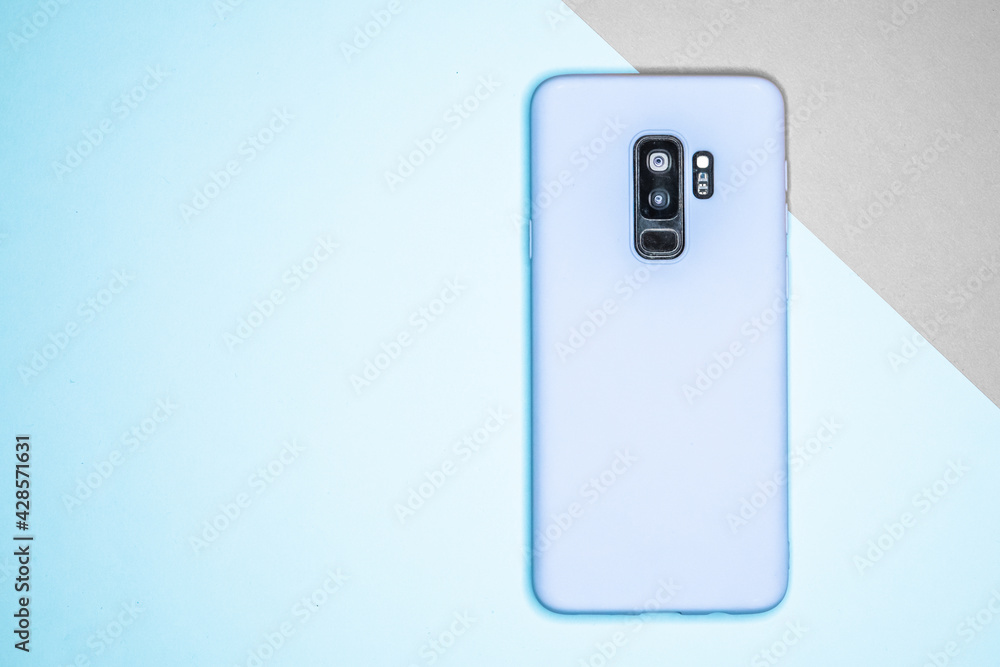 Poster top view of mobile phone with blue case isolated on blue and gray background - space for text