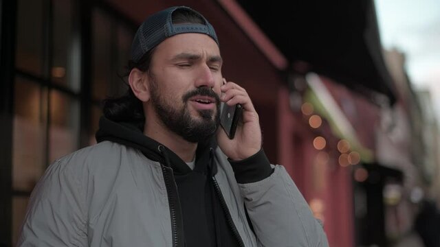 Young, modern handsome man talking on the phone on the street.