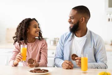 Fototapeta na wymiar Cheerful african american daughter and dad having breakfast