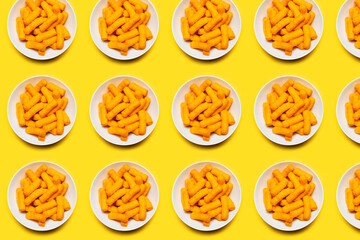 Pattern of white bowls with corn puffs on yellow background.