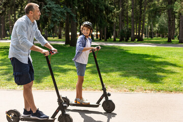 Happy guy with daddy having ride on e-scooter © Prostock-studio