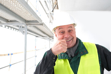 cheerful senior male builder foreman, worker in white hardhat, in work clothes on construction...