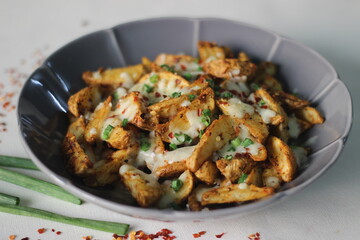 Cheesy potato wedges made by baking air fried potato wedges after sprinkling it with shredded...