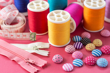 Composition with threads and sewing accessories on pink background