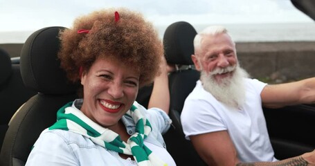 Multiracial senior couple having fun inside convertible car in summer vacation - Joyful elderly people lifestyle concept - Powered by Adobe
