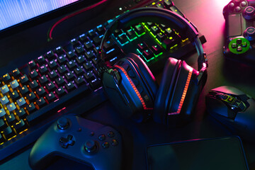 gamer work space concept, top view a gaming gear, mouse, keyboard, joystick, headset with rgb color on black table background.