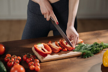 Top view of woman's hand cutting green celery stalk on chopping board. Female vegetarian slicing vegetables for crispy salad. Healthy eating concept.
