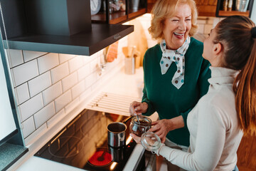 Mother and daughter making coffee together. The daughter helps her older mother to making coffee.