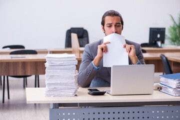 Young male employee unhappy with excessive work in the office
