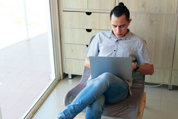Man sitting in the living room of his house, using a laptop to work from home