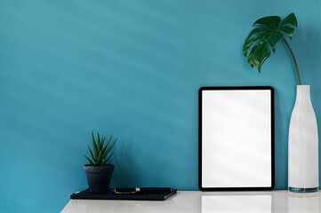 Mockup blank screen tablet with decoration on white table and blue wall background.