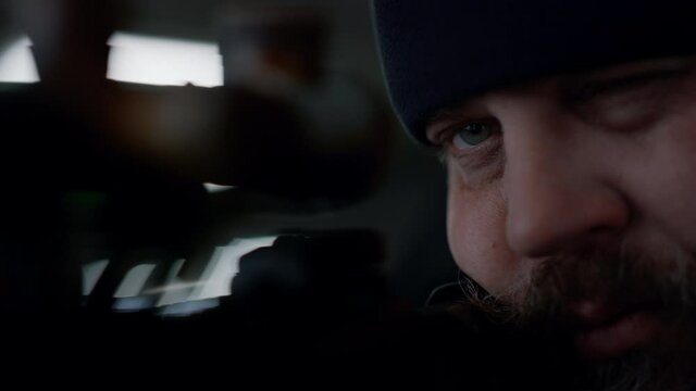 Hitman looking through scope on rifle. Soldier focused on aim in optical sight