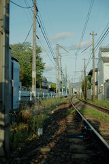 Fototapeta na wymiar Vertical photo of railway tracks in the morning. Electrical wire and cables. Local tram train tracks in Kyoto, Japan.