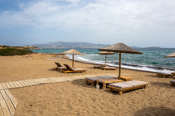 Sun beds and umbrellas at Soros beach on Antiparos Island. A wonderful beach with the golden sand and azure waters. Cyclades, Greece