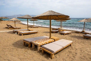 Sun beds and umbrellas at Soros beach on Antiparos Island. A wonderful beach with the golden sand and azure waters. Cyclades, Greece