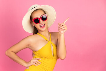 Beautiful, Sexy asian woman in  bikini and smiling standing on pink background isolated .Summer vocation happy trip concept.