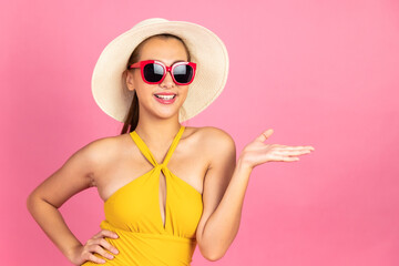 Beautiful, Sexy asian woman in  bikini and smiling standing on pink background isolated .Summer vocation happy trip concept.