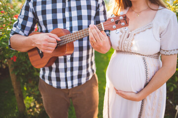 husband playing ukulele next to pregnant wife