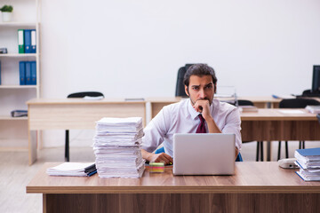 Fototapeta premium Young male employee unhappy with excessive work in the office