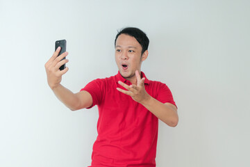 Wow face of Young Asian man shocked what he see in the smartphone on isolated grey background.