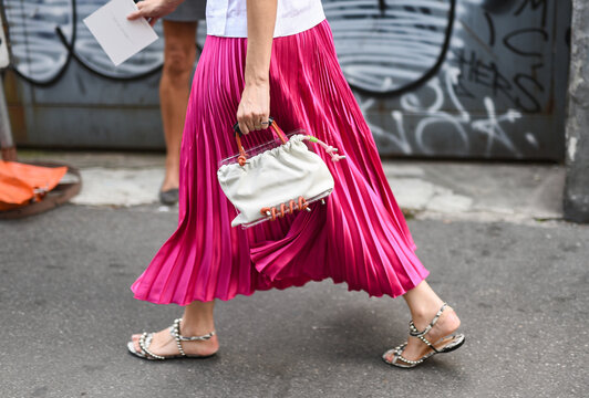 Milan, Italy - September 19, 2018: Woman wearing pink skirt, white bag  and sandals walking on the streets of Milan, detail.