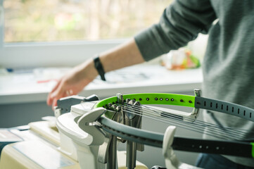 Close-up of tennis racket on electronic stringing machine. Process of replacement synthetic gut string before game. Hands of stringer.