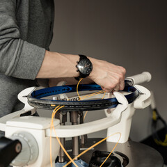 Close-up of tennis racket on electronic stringing machine. Process of replacement synthetic gut...