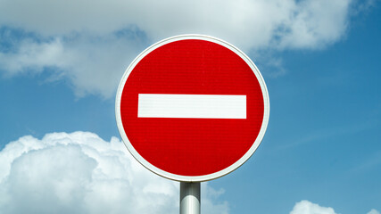 Close-up on a traffic sign, forbidden, against a background of blue sky with white cottony clouds