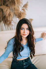 Portrait of attractive caucasian woman with brunette hair in bright living room with white walls,...