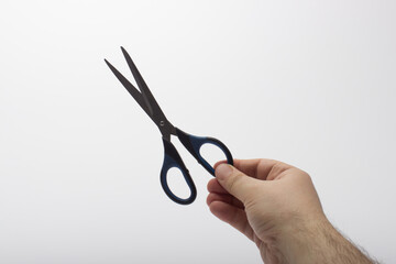 Scissors in the hands of a man. Stationery scissors in hand isolated on a white background.