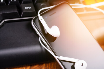 Smartphone and headphones on a laptop keyboard. Clubhouse is an audio chat app